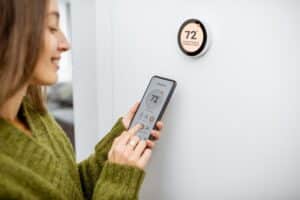 woman-setting-thermostat-with-smartphone-app